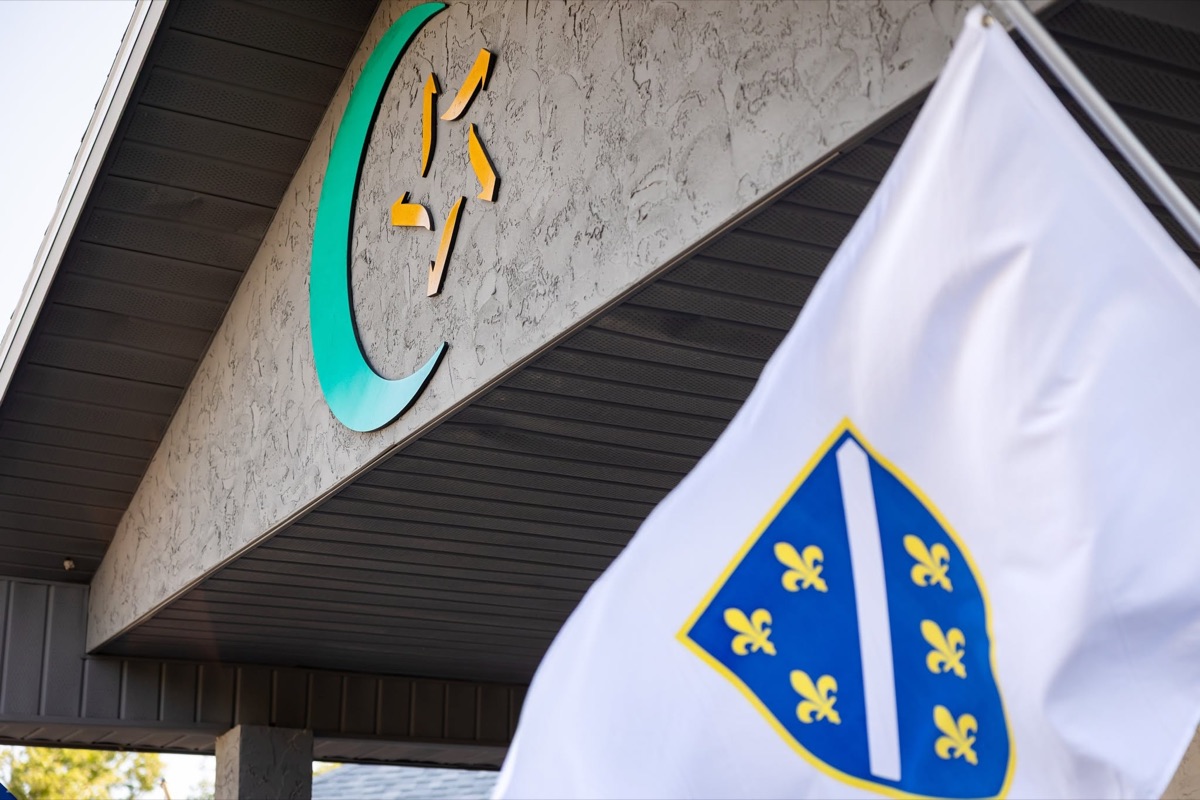 The crescent and star on the mosque building beside the flag of Bosnia and Herzegovina