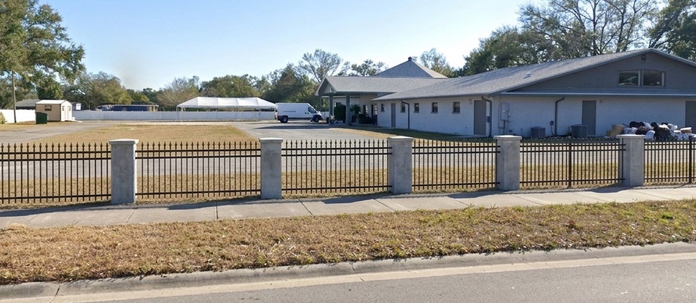 Rendering of the mosque grounds seen from the road, with a new black metal fence between light stone pillars along the sidewalk