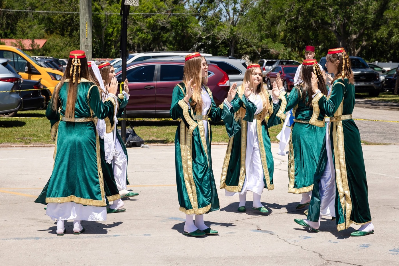 Young women in traditional green dresses performing a folk dance outdoors